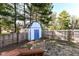 Fenced backyard features a storage shed with painted blue door in a grassy, tree-lined yard at 8506 Friendship Ln, Indianapolis, IN 46217