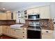 Bright kitchen equipped with stainless steel appliances, ample cabinet space, and mosaic tile backsplash at 8543 W County Road 600 S, Coatesville, IN 46121