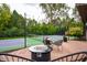 Outdoor tennis court on wood deck featuring string lights, seating, and view of lush landscaping at 8737 Chateaugay Dr, Indianapolis, IN 46217
