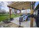 Inviting backyard patio area with a wooden pergola, comfortable seating, and manicured landscaping at 10047 Perlita Pl, Fishers, IN 46038