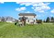 Sprawling backyard with playset, green grass, and trees under a bright blue sky at 10465 Long Branch Dr, Brownsburg, IN 46112