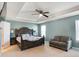 Bright and spacious main bedroom featuring tray ceilings, a ceiling fan, and sitting area with couch at 10465 Long Branch Dr, Brownsburg, IN 46112