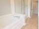 Corner tub and glass shower enclosure with tan colored tile flooring at 12332 Cobblefield Ct, Fishers, IN 46037