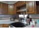 Kitchen showing stainless steel stove and cooktop with wooden cabinets and stone-style backsplash at 13065 Allman Dr, Mooresville, IN 46158