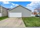 A two-car garage with a vinyl siding exterior, a grassy lawn, and a concrete driveway at 14444 Black Farm Dr, Noblesville, IN 46060
