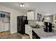 Well-lit kitchen featuring granite counters, stainless steel sink, and black appliances with laundry room access at 14444 Black Farm Dr, Noblesville, IN 46060