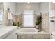 Bright bathroom with an elegant white tub surrounded by neutral tile and adorned with indoor plants at 1527 N Washington St, Danville, IN 46122