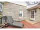Exterior shot of the front porch of a stone-clad home with wood floors and a relaxing chaise lounge at 1527 N Washington St, Danville, IN 46122