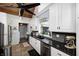 Kitchen featuring white cabinetry, black countertops, stainless steel appliances, and a view to a laundry area at 1527 N Washington St, Danville, IN 46122