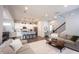 Open-concept living room showcases a staircase, gray sofas, modern decor, and flows into a kitchen with a central island at 1534 Cloverdon Dr, Westfield, IN 46074