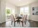 Sunlit dining room with a glass table, six chairs, and large windows overlooking the outdoor space at 1571 Beyers St, Fortville, IN 46040