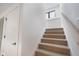 Carpeted staircase with neutral carpet, white risers, white handrail, and black frame window at 1822 Central Ave, Indianapolis, IN 46202