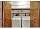 Practical laundry room featuring a washer, dryer, shelving for storage and bi-fold doors at 1829 Catalano Dr, Indianapolis, IN 46214