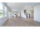 Bright and airy living room featuring wood floor, staircase, large windows, and open concept kitchen at 18944 Seaforth Way, Westfield, IN 46074