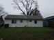 The back of the house with a spacious yard, a lush lawn, and mature trees at 1931 Brentwood Dr, Anderson, IN 46011