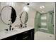 Stylish bathroom featuring double vanity, decorative mirrors, and tiled shower with built-in shelving at 2103 Postmaster Ln, Greenfield, IN 46140