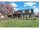 Beautiful home featuring green siding, black trim, lush lawn, mature trees, and a pergola-covered porch at 2103 Postmaster Ln, Greenfield, IN 46140