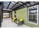 View of a covered patio with black pergola and chairs with bright yellow cushions, adjacent to the brick home at 2103 Postmaster Ln, Greenfield, IN 46140