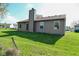 A grassy backyard featuring the home's exterior with vinyl siding and a chimney at 2206 Tansel Crossing Cir, Indianapolis, IN 46234