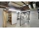 Unfinished basement features laundry hookups, exposed ductwork, and storage shelving at 2330 Harlan St, Indianapolis, IN 46203