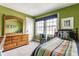 Bright green bedroom with a wooden dresser, complemented by natural light and a cozy teddy bear at 4451 N Washington Blvd, Indianapolis, IN 46205