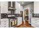 Bright kitchen features white cabinets, stainless steel appliances, stylish backsplash and hardwood floors at 4451 N Washington Blvd, Indianapolis, IN 46205
