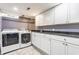 Functional laundry room with white cabinets, granite countertops, sink, washer, and dryer at 4451 N Washington Blvd, Indianapolis, IN 46205