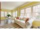 Bright sunroom with a white sofa, colorful pillows, a bistro table, and many windows to bring in natural light at 4451 N Washington Blvd, Indianapolis, IN 46205