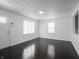 Bright living room with two large windows and dark hardwood floors, next to a white front door at 4897 Walker St, Greenwood, IN 46143