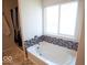 Modern bathtub with decorative tile accents, bright lighting, and a window at 5051 Arling Ct, Indianapolis, IN 46237