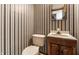 Charming bathroom featuring floral wallpaper, a toilet, and a pedestal sink with mirrored vanity at 5124 Mccray St, Indianapolis, IN 46224