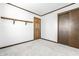 Neutral carpeted bedroom with white walls, a wood door, and open shelving for storage at 5124 Mccray St, Indianapolis, IN 46224