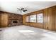 Living room featuring a brick fireplace, wood paneling, carpet and a ceiling fan at 5124 Mccray St, Indianapolis, IN 46224