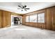 Living room with neutral carpet, ceiling fan, and wood-paneled walls with large windows at 5124 Mccray St, Indianapolis, IN 46224