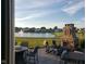 A backyard stone fireplace sits on a stone patio, with a manicured lawn and houses in the background across the pond at 5178 Aegis Dr, Noblesville, IN 46062