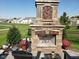 An outdoor stone fireplace sits on a stone patio, with a manicured lawn and houses in the background at 5178 Aegis Dr, Noblesville, IN 46062