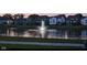 Scenic view of a community pond at dusk, featuring a decorative fountain and reflecting the lights of nearby homes at 5178 Aegis Dr, Noblesville, IN 46062