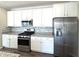 Modern kitchen with white cabinets, stainless steel appliances, and gray backsplash at 5493 W Woodhaven Dr, McCordsville, IN 46055
