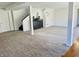 Large finished basement area with neutral carpeting, black accent furniture and access to stairs at 5739 E 62Nd Pl, Indianapolis, IN 46220