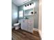 Bathroom featuring white cabinets, updated mirror and light fixtures, with blue paint and laminate flooring at 601 Duane St, Franklin, IN 46131