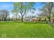 A sprawling backyard with a well-manicured lawn and mature trees frames the rear of this two-story home at 7205 Steven Ln, Indianapolis, IN 46260