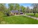 Spacious front yard showcasing a well-maintained lawn, mature trees, and a charming brick home with attached garage at 7205 Steven Ln, Indianapolis, IN 46260
