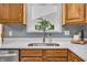Close-up of kitchen sink with modern faucet, white countertops, and oak cabinets at 7205 Steven Ln, Indianapolis, IN 46260
