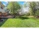 Spacious backyard with lush green lawn and mature trees, featuring a wooden deck attached to the home at 7728 Mallard Way, Indianapolis, IN 46256
