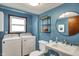 Blue bathroom with modern fixtures, a laundry area with washer and dryer, and a round mirror at 7728 Mallard Way, Indianapolis, IN 46256