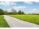 Gravel driveway in the distance with green grassy lawn and distant view of the brick house at 8362 N County Road 650 E, Brownsburg, IN 46112
