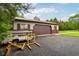 Outbuilding with large garage door and asphalt driveway with trailer and automotive jacks at 8362 N County Road 650 E, Brownsburg, IN 46112
