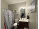 Well-lit bathroom with a sink vanity, framed mirror, and shower with patterned curtain at 914 Baden Manor Dr, Indianapolis, IN 46217