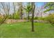 Landscaped backyard with a lush green lawn, mature trees, and a wooden fence offers plenty of space to relax at 9531 Charter Dr, Indianapolis, IN 46250