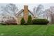 A well-manicured backyard featuring a stone chimney, lush green lawn, and mature landscaping at 11203 Westminster Way, Carmel, IN 46033